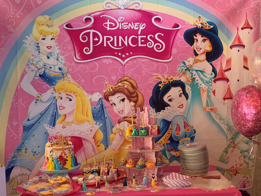 Pink and gold princess birthday party setup with custom cake, decorated cookies, and balloon arch.